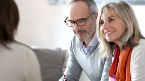 Smiling couple sat with advisor - Totally Life